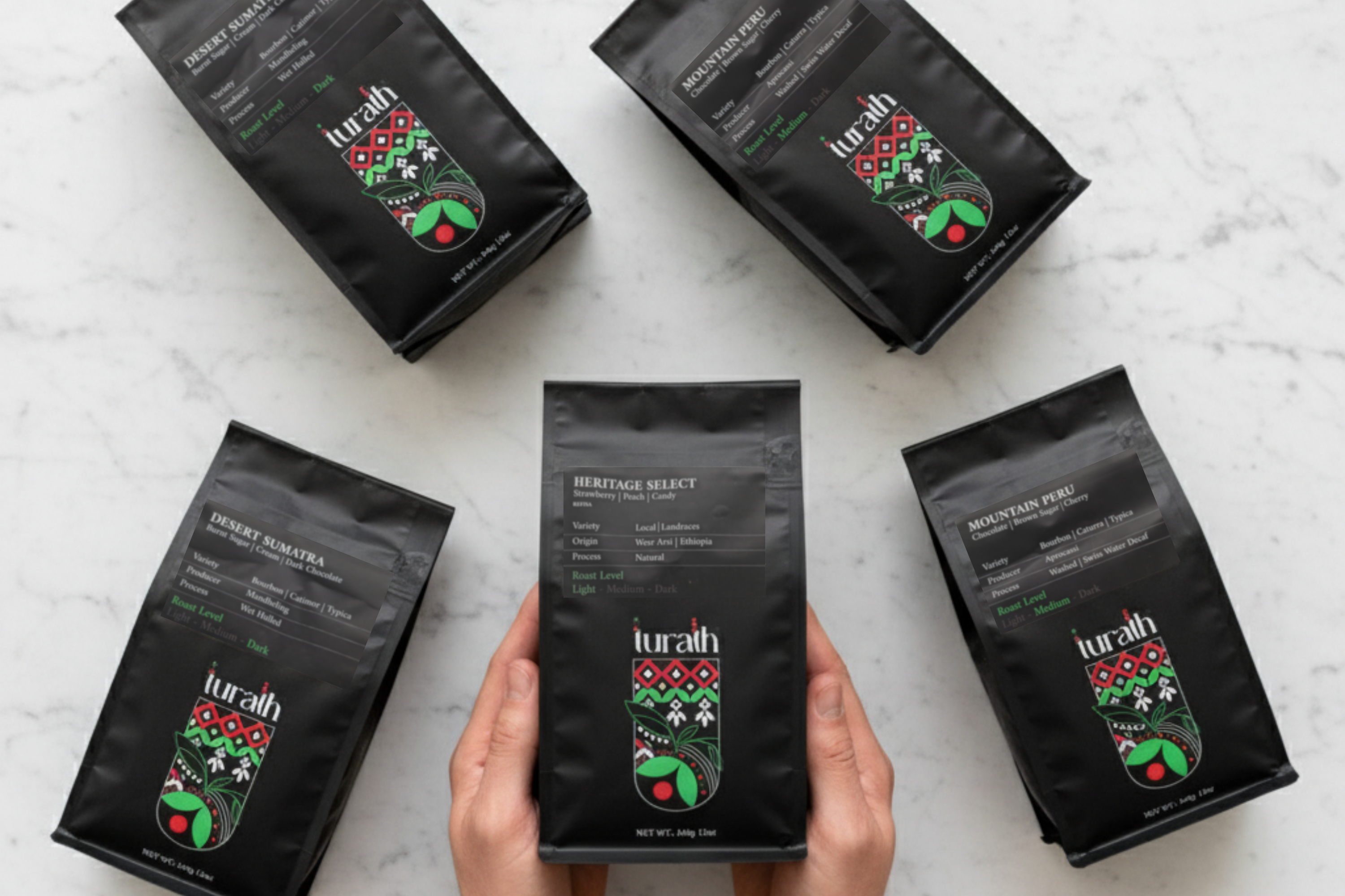 Turath coffee bags displayed over a white marble background and a person holding one bag in their hand 